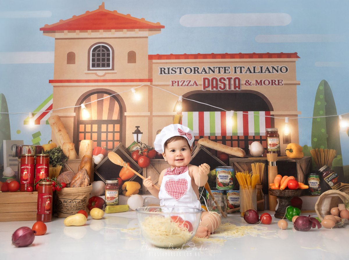 Adorable baby dressed as a little chef playing with spaghetti during a Baby Chef Photoshoot in Sydney at Blossom Brook Studio.