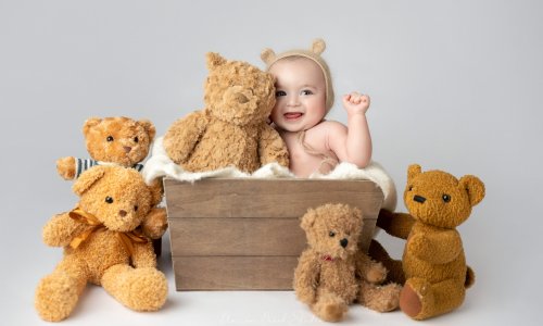 Baby surrounded by plush teddy bears.