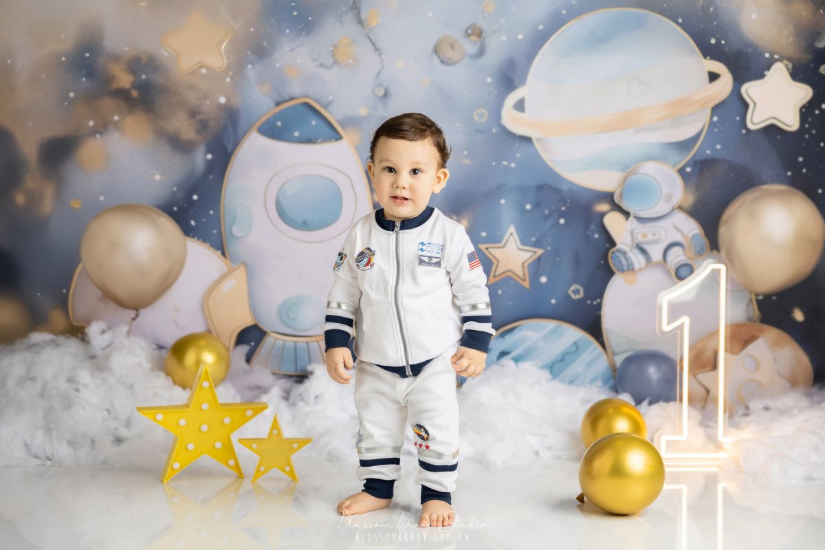 Adorable baby dressed as an astronaut during a space-themed First Birthday Photoshoot Sydney by Blossom Brook Studio, surrounded by planets, stars, and balloons.