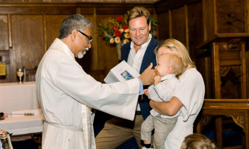 christening photography priest bless the baby boy by touching his nose