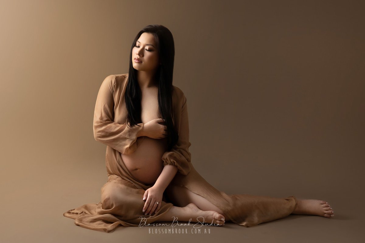Elegant Pregnancy Photoshoot in Sydney studio featuring an expecting mother in a flowing sheer gown, captured by Blossom Brook Studio.