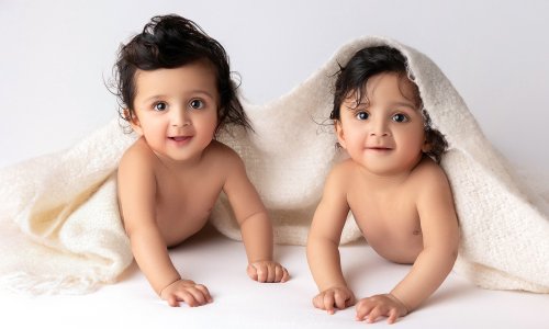 Adorable twin babies under a blanket captured during a professional baby photography Sydney session at Blossom Brook Studio.