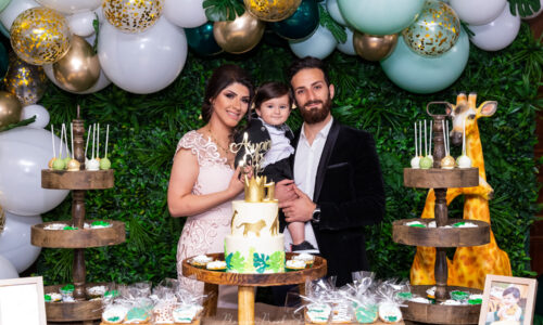 Elegant family posing at a jungle-themed celebration table with cake and balloons, perfect example of Birthday Party Images.