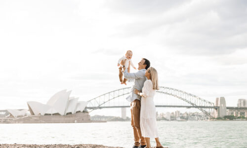 A joyful family captured during a Royal Botanic Gardens family photography session with the Sydney Opera House and Harbour Bridge in the background.