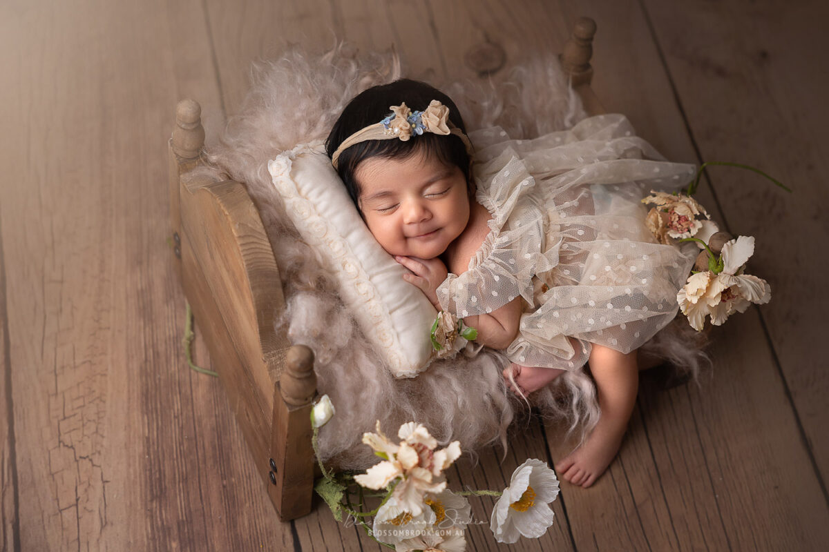 newborn baby girl sleep in a wooden bed smiling