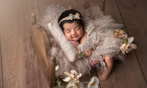 newborn baby girl sleep in a wooden bed smiling